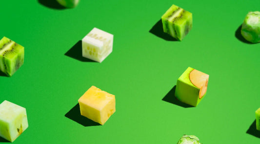 Colorful cubes of fresh fruit and vegetables on green background – natural whole food ingredients for plant-based supplements