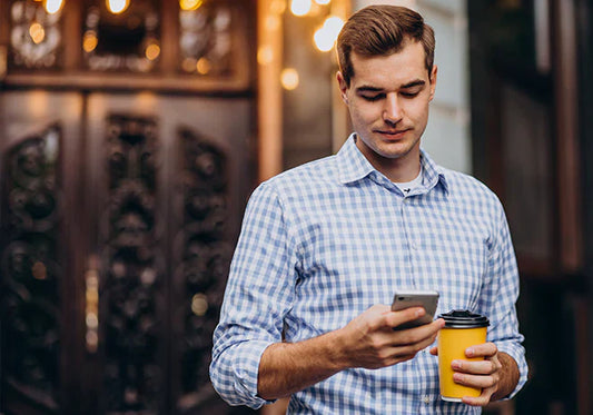 Man holding coffee and phone during intermittent fasting routine