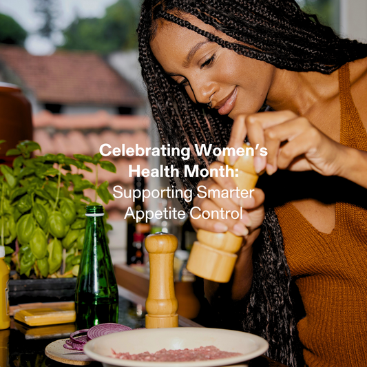 Woman preparing food in a kitchen, grinding seasoning over a meal, representing healthy eating habits and smarter appetite control during Women’s Health Month